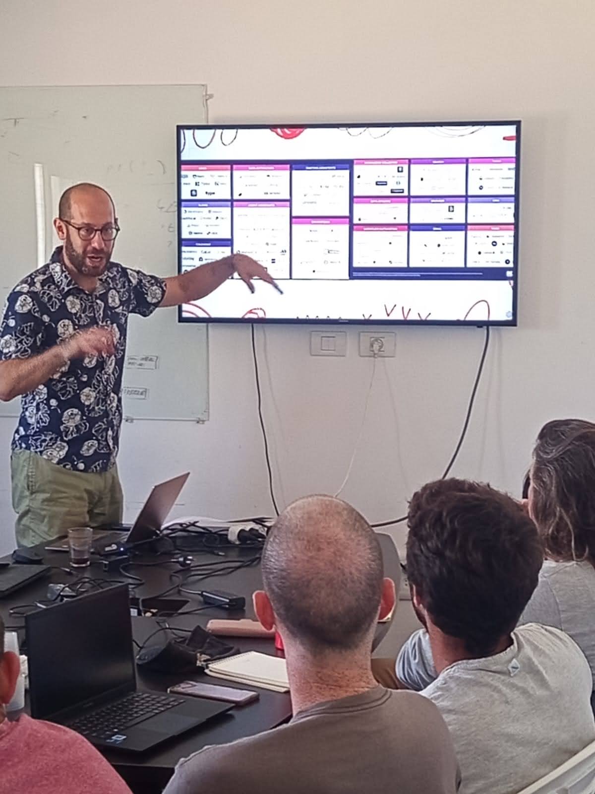 דני שקט מוביל סדנת AI — מצביע על מסך כלי AI בפני הקהל